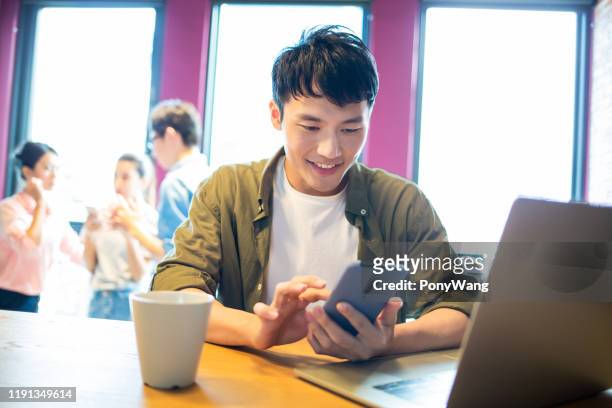 man gebruik smartphone en laptop - korean man stockfoto's en -beelden