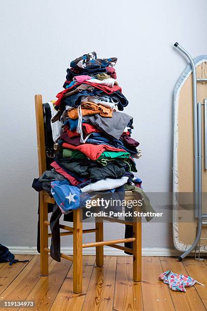 a big untidy stack of clean clothes waiting to be ironed - messy room stock-fotos und bilder