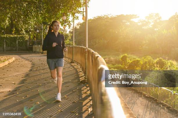young asian woman running in the park with sunshine warm light. - hot boy body stock pictures, royalty-free photos & images