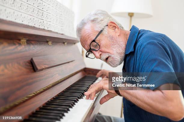 the elderly man enjoy playing piano at home. - musical instruments stock pictures, royalty-free photos & images