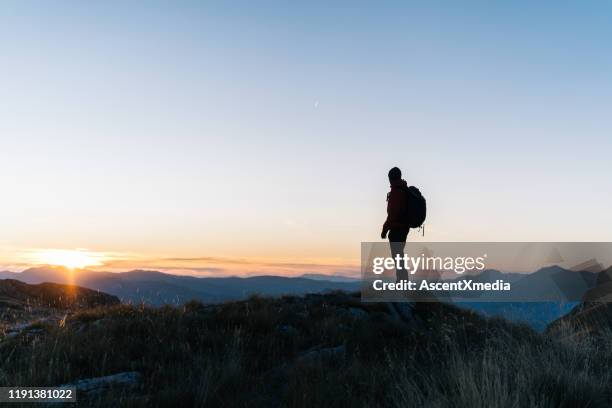hiker relaxes above mountain valley at sunrise - standing on mountain peak stock pictures, royalty-free photos & images