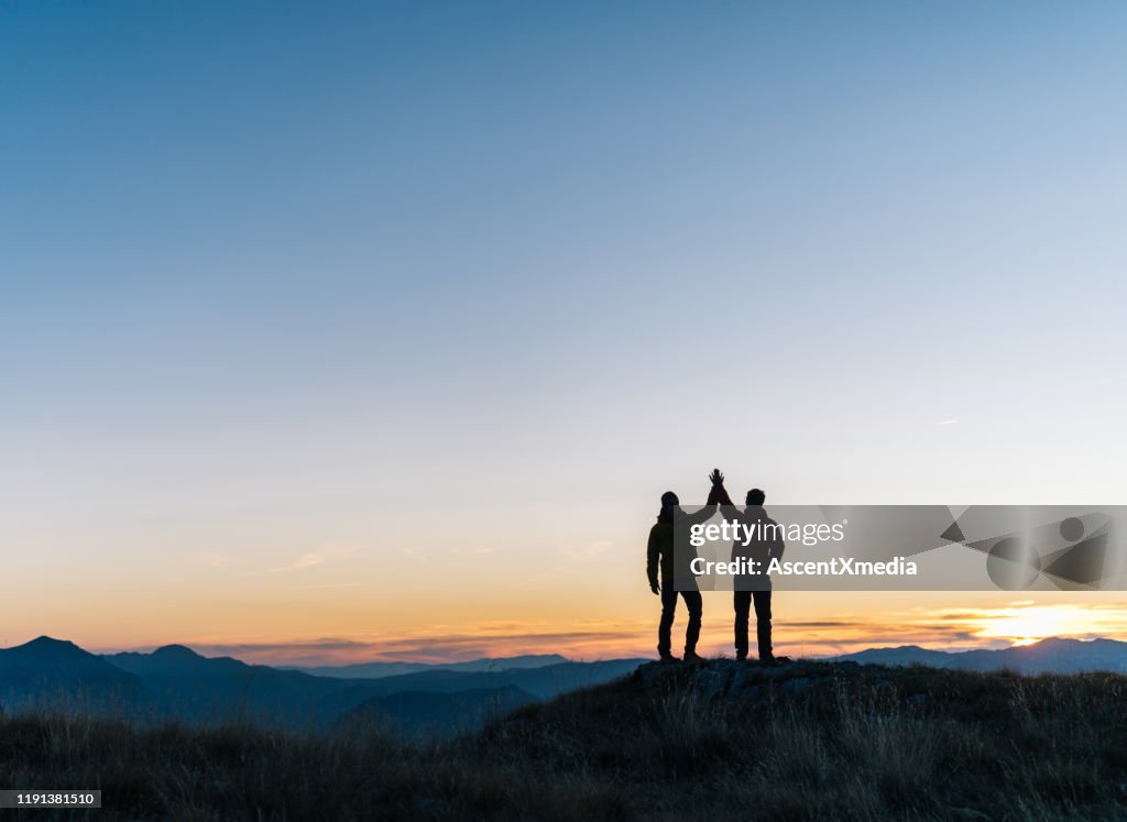 Hikers relaxes above mountain valley at sunrise