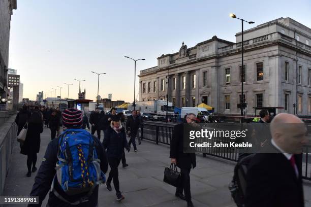 Commuters walk across London Bridge and past Fishmongers' Hall early morning as the bridge is reopened after the recent stabbing attack on December...