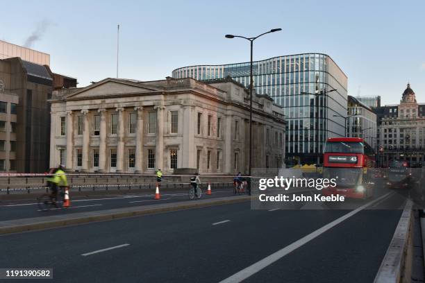 Cyclists and busses cross London Bridge and past Fishmongers' Hall early morning as the bridge is reopened after the recent stabbing attack on...