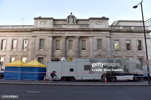 Cyclist crosses London Bridge and past forensic tents and truck station outside Fishmongers' Hall early morning as the bridge is reopened after the...