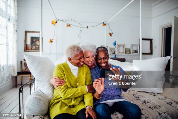 Three mature women looking at smart phone / London, UK.