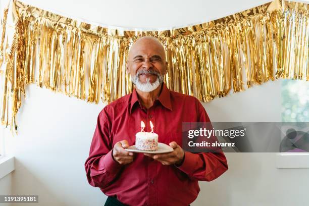 man holding birthday cake with burning candles - holding birthday cake stock pictures, royalty-free photos & images
