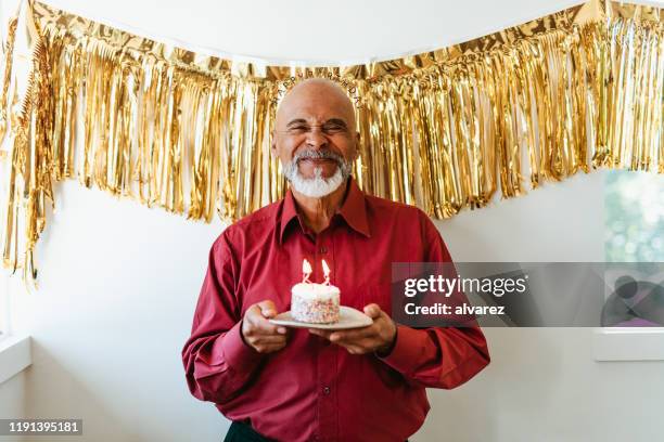 man holding birthday cake with burning candles - senior birthday stock pictures, royalty-free photos & images