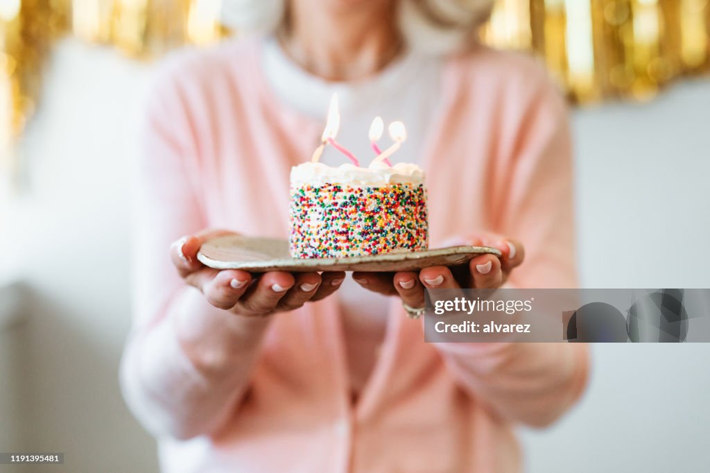 Retired woman holding cake with birthday candles