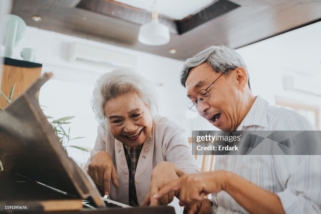 Thai senior couple enjoy playing paino at home