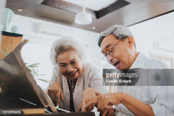 thai senior couple enjoy playing paino at home - piano stock pictures, royalty-free photos & images