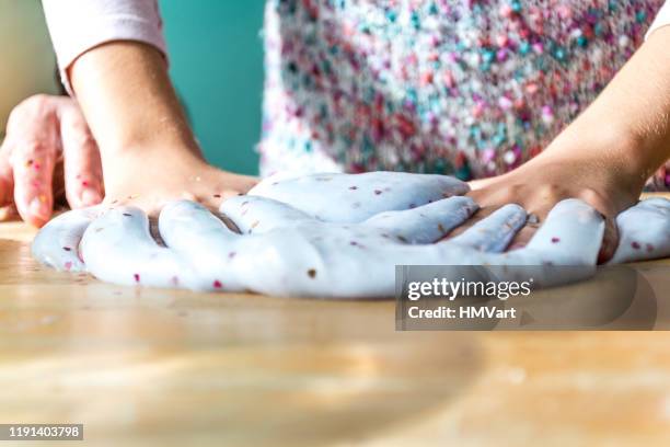 kleindochter besteedt tijd samen met grootmoeder maken glinsterende slime in binnenlandse keuken - slime stockfoto's en -beelden