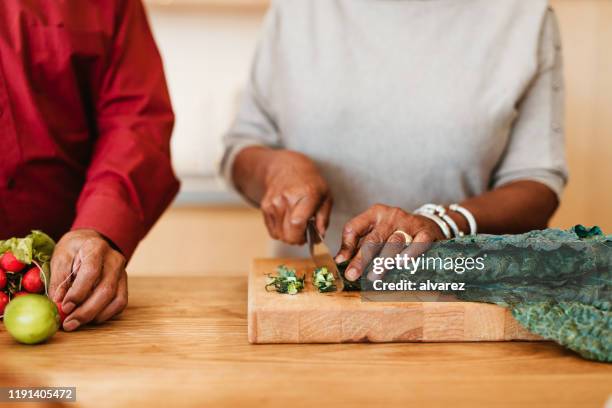 woman chopping chard on cutting board by husband - healthy eating seniors stock pictures, royalty-free photos & images