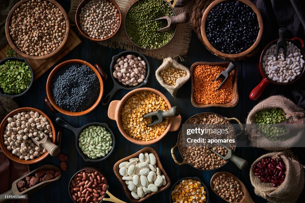 Top view low key of a large variety of dry beans. Shot from above on rustic wooden table