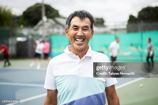 portrait of senior man enjoying tennis - japanese tennis stock-fotos und bilder