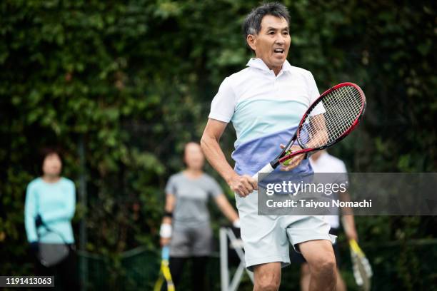 senior man playing tennis seriously - japanese tennis photos et images de collection