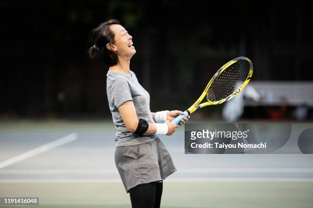 a woman who enjoys tennis at night - japanese tennis photos et images de collection