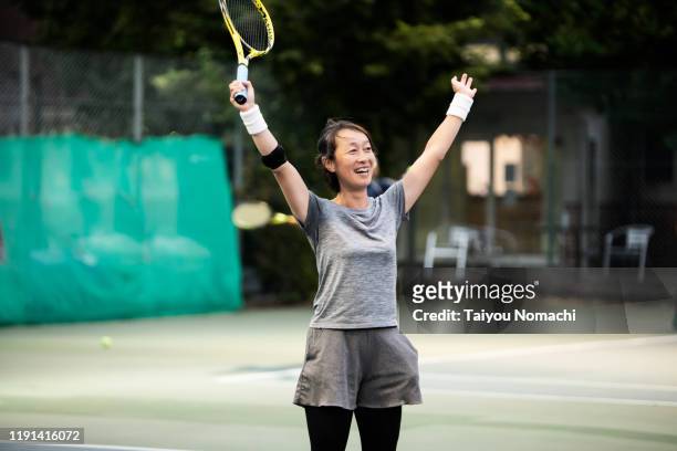 a woman who expresses joy in winning a tennis game - match sport stock-fotos und bilder