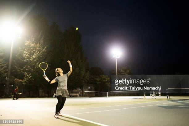 a woman who throws a ball high and hits a serve - japanese tennis stock pictures, royalty-free photos & images