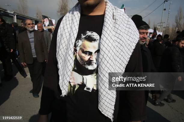 An Iranian, wearing a t-shirt with a picture of slain commander Qasem Soleimani, takes part in a demonstration in the capital Tehran on January 3,...