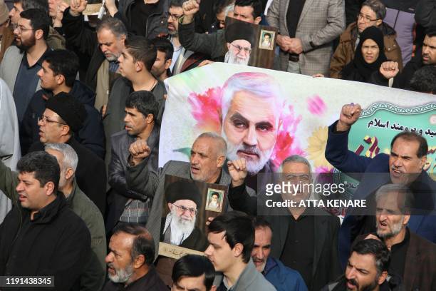 Iranians march with a banner bearing an illustration of Iranian Revolutionary Guards Major General Qasem Soleimani during a demonstration in Tehran...