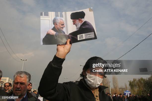 Man holds a picture of Iran's supreme leader Ayatollah Ali Khamenei with Iranian Revolutionary Guards Major General Qasem Soleimani during a...