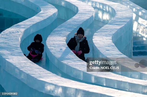 Tourists slide on an ice sculpture ahead of the opening of the Harbin International Ice and Snow Festival in Harbin, in China's northeast...