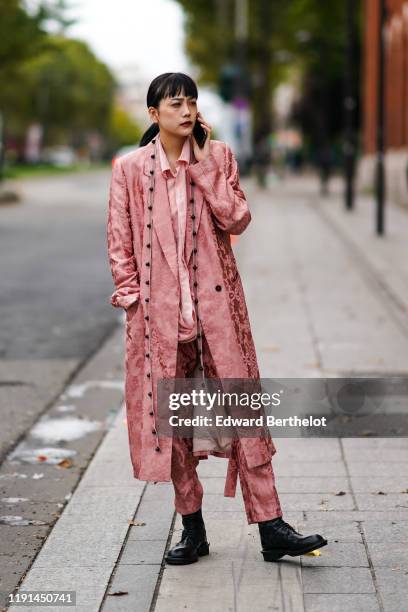 Guest wears a pink shirt, a long lustrous silky coat with floral embroidery, black leather shoes, outside Ann Demeulemeester, during Paris Fashion...