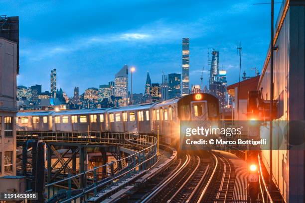 approaching train in queens and manhattan skyline, new york city - an evening with 7 at 7 on the 7th stockfoto's en -beelden
