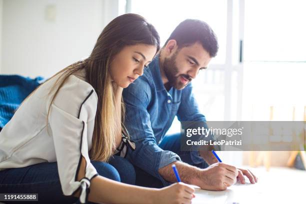 young couple signing contract for their new house - couple signing stock pictures, royalty-free photos & images