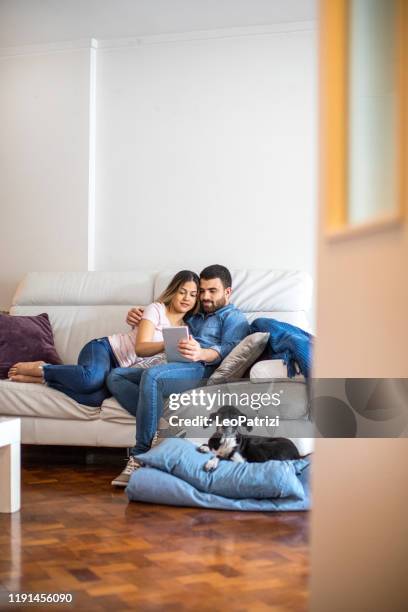 young latin american couple at home - dog sofa stock pictures, royalty-free photos & images