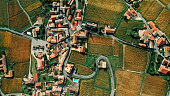 Aerial shot of a French village with orange roofs, winding roads and surrounded by vineyards - stock photo
