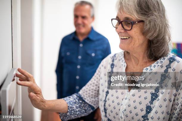 senior woman setting burglar alarm - alarm system stock pictures, royalty-free photos & images