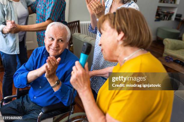 senior woman singing during karaoke party with friends - senior man dancing on table stock pictures, royalty-free photos & images