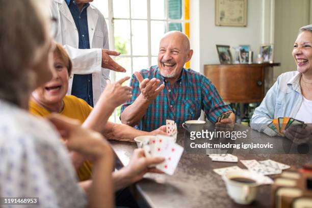 enjoying their card game in nursing home - senior men playing cards stock pictures, royalty-free photos & images