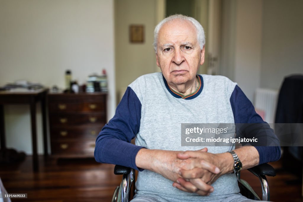 Portret van een oudere man in een rolstoel thuis