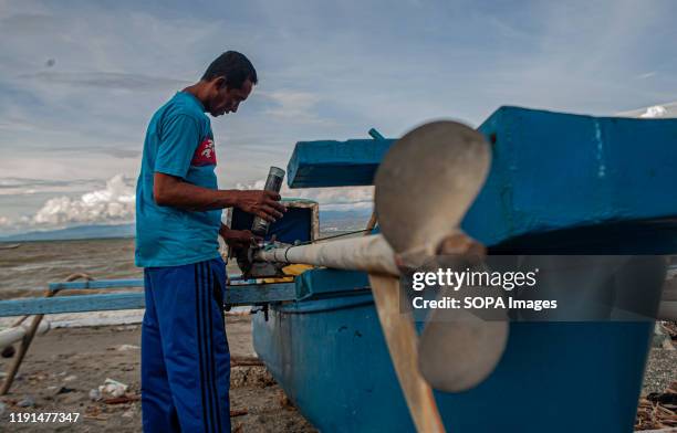 Fisherman fixes a broken boat engine. High waves in the waters of Palu Bay forced Hundreds of fishermen in the village of Lere to anchor their boats....