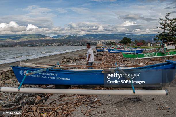 Fisherman walks passed an anchored boat. High waves in the waters of Palu Bay forced Hundreds of fishermen in the village of Lere to anchor their...