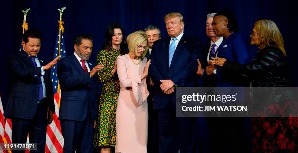 President Donald Trump stands in a prayer circle with faith leaders during a 'Evangelicals for Trump' campaign event held at the King Jesus...