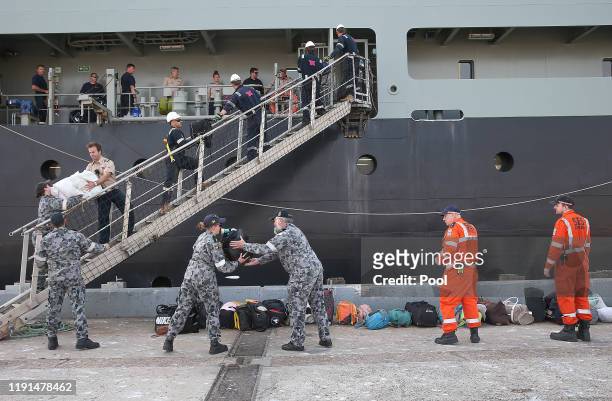 Navy crew unload luggage as evacuees from Mallacoota arrive aboard the navy ship MV Sycamore on January 4, 2020 at the port of Hastings, Australia....