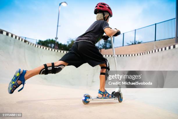 a 7 year old boy on a scooter at the skate park - stunts and daredevils stock pictures, royalty-free photos & images