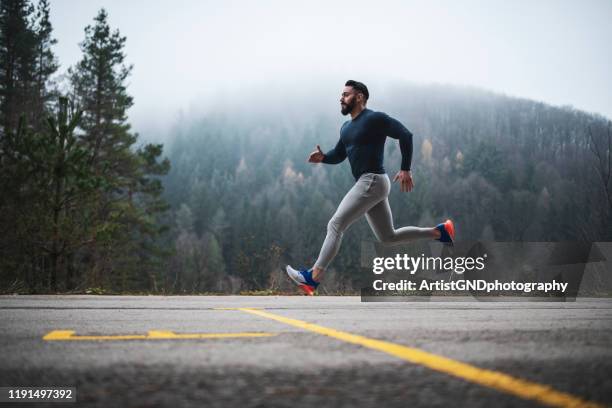 sportsman running on the road in autumn. - winter running stock pictures, royalty-free photos & images