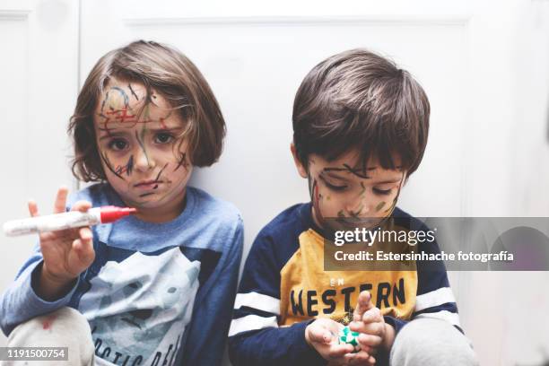 photograph of a naughty boy and girl who have painted their face with a marker pen - sad girl drawing photos et images de collection