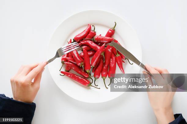girl hands with fork and knife, woman cuts red hot spicy cayenne pepper on a white plate. proper nutrition, vegetarian food, healthy lifestyle diet concept. - red chili pepper stock pictures, royalty-free photos & images