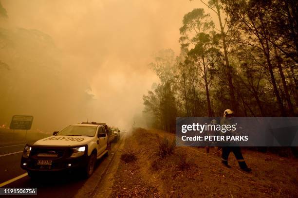 Firefighters tackle a bushfire in thick smoke in the town of Moruya, south of Batemans Bay, in New South Wales on January 4, 2020. - Up to 3,000...