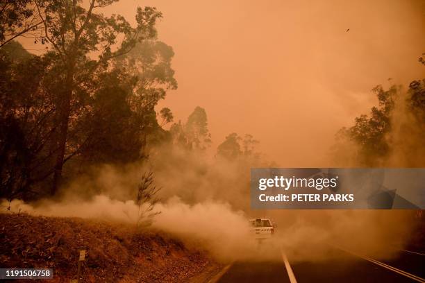 Firefighters tackle a bushfire in thick smoke in the town of Moruya, south of Batemans Bay, in New South Wales on January 4, 2020. - Up to 3,000...