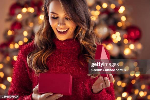 hermosa chica sentada en un ambiente acogedor cerca del árbol de navidad - gift fotografías e imágenes de stock