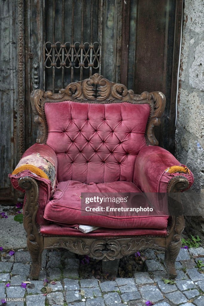 Abandoned old purple velvet armchair in the street,Alacati.