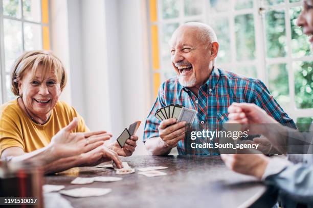 grupo de personas mayores jugando a las cartas juntos - actividad fotografías e imágenes de stock