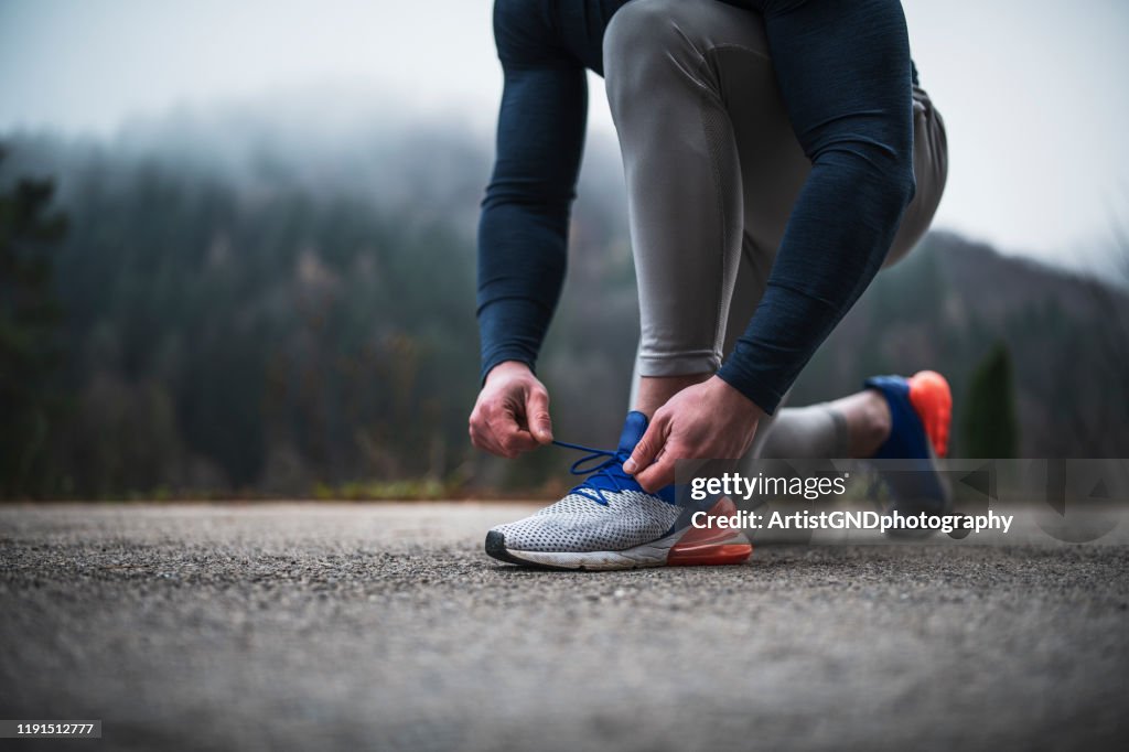 Athlete tying shoelace outdoor.